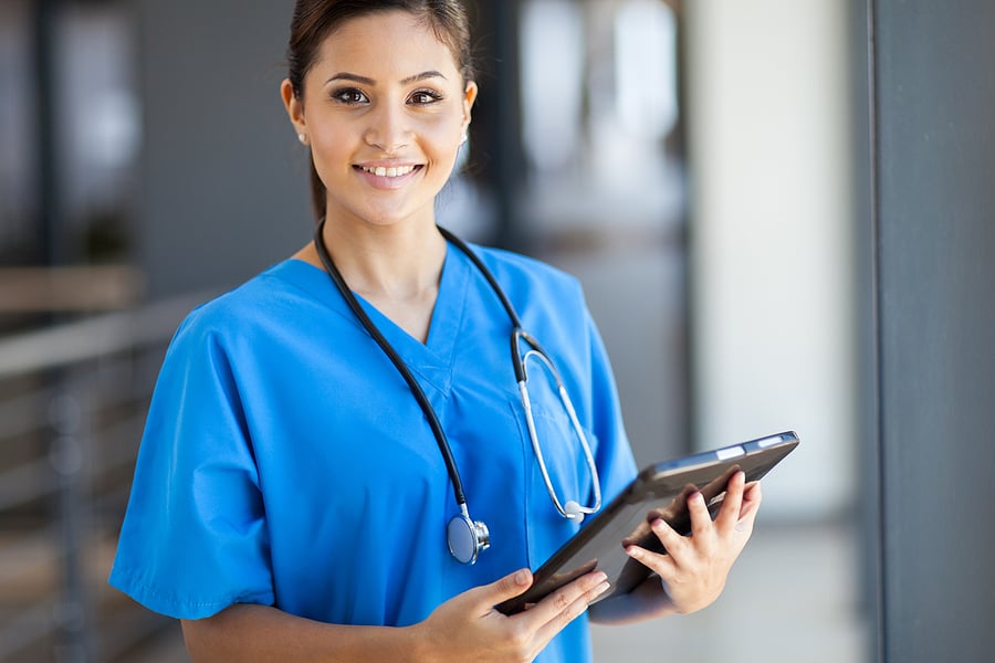 Medical assistant standing in the hospital holding a clipboard.