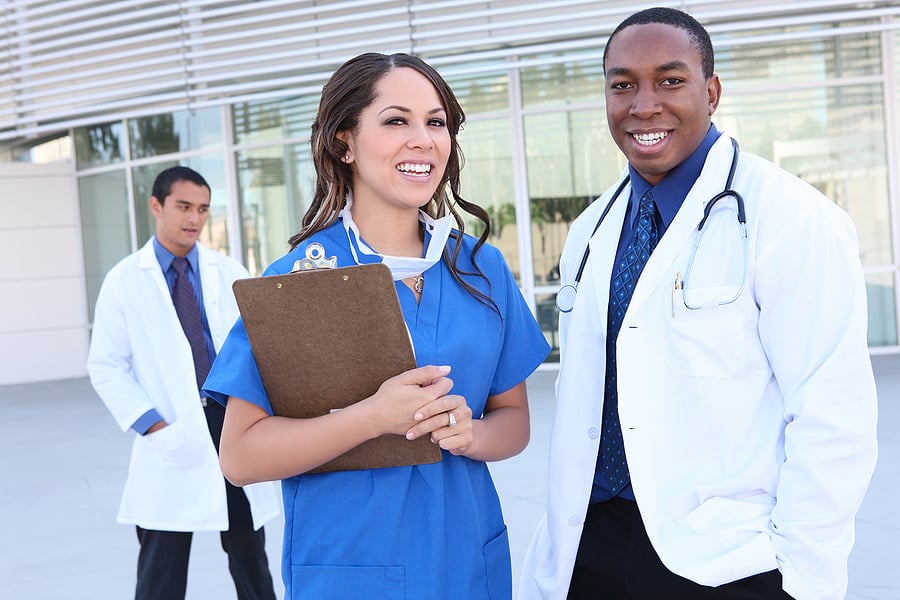 A doctor and a medical assistant standing outside a medical facility.