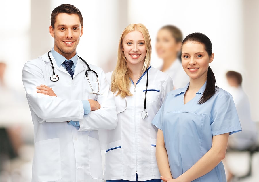 A doctor, nurse, and medical assistant standing in a hospital.