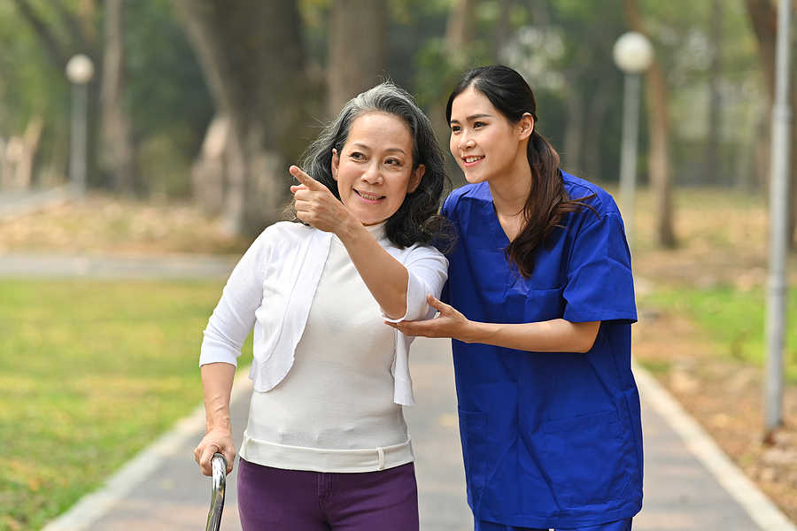 medical assistant helping and accompanying an elderly patient on a walk outside