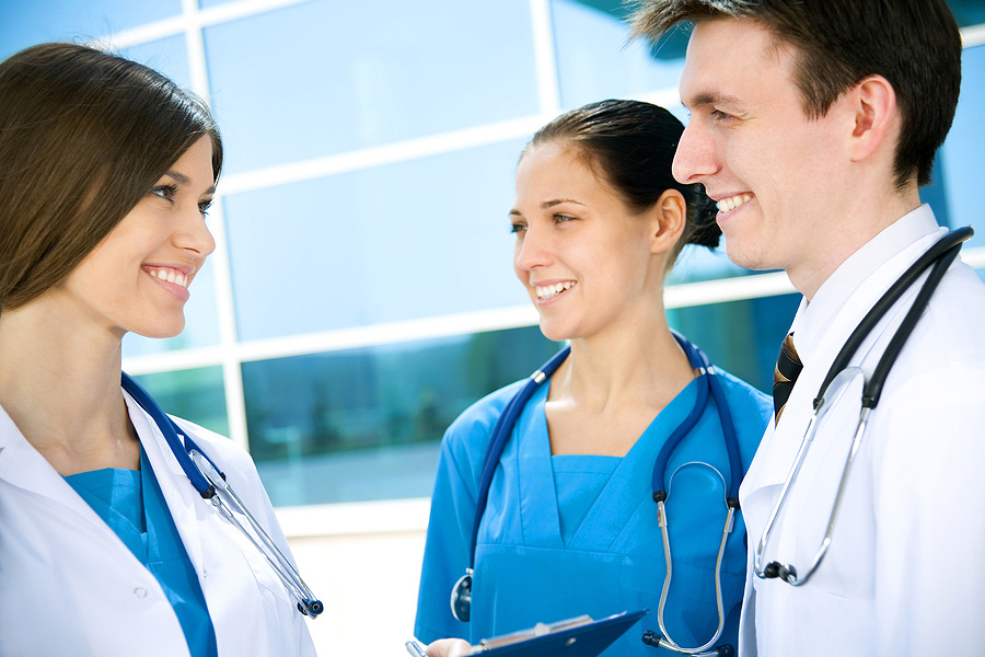 Three medical professionals talking outside of a medical facility.