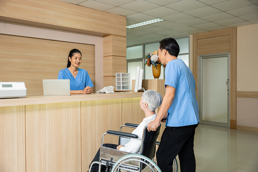 Medical assistant pushing an elderly patient in a wheelchair 
