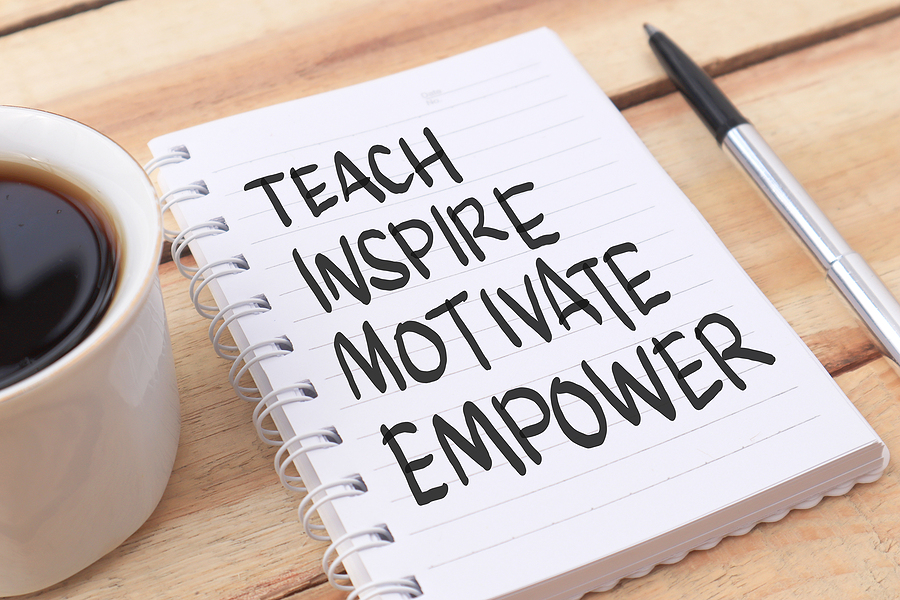 Note pad with words TEACH INSPIRE MOTIVATE EMPOWER written in black marker.