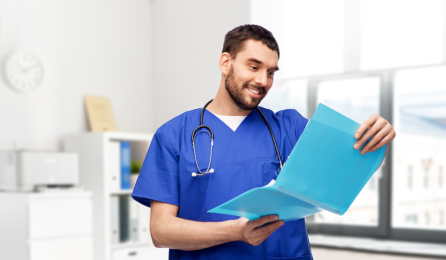 Male medical assistant looking at a patient file before an appointment.