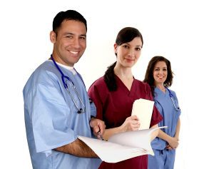 Male medical assistant and two female medical assistants smiling at camera in scrubs. 