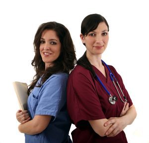Two female medical assistants smiling at the camera, wearing scrubs. 