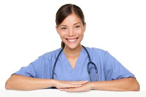 Female nurse wearing blue scrubs and smiling at the camera. 