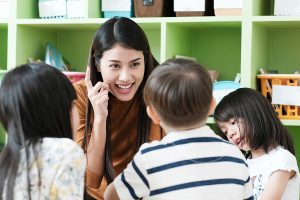 Close up of an early childhood educator talking to a small group of young students. 