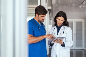 Female doctor and male medical assistant looking at a patient chart discussing something. 