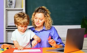 Female teacher helping a young student with a lesson. 