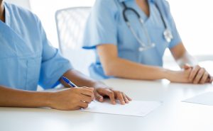 Medical assisting students wearing blue scrubs and taking notes in class. 