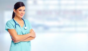 Woman wearing light green scrubs with her arms folded, smiling at the camera. 