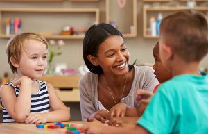 Teacher and students using wooden shapes at a table. 