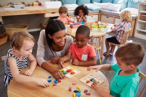 Female preschool teacher helping a group of students learn shapes. 